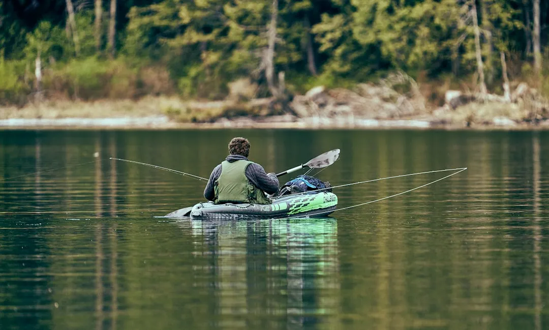 Kayak fishing on a calm lake with a fisherman casting