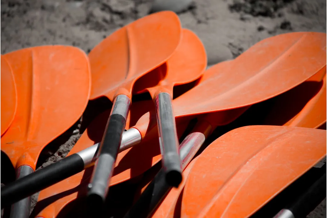 Kayak paddle resting on rock at sunset